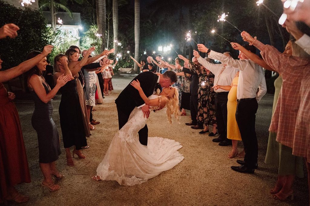 Bride and groom celebrate with a sparkler send-off, a magical moment for those planning your Queensland wedding, surrounded by guests and festive lights.