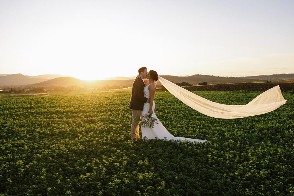 Couple shares a romantic moment in the golden hour sunlight, perfect for those planning your Queensland wedding in scenic outdoor settings.